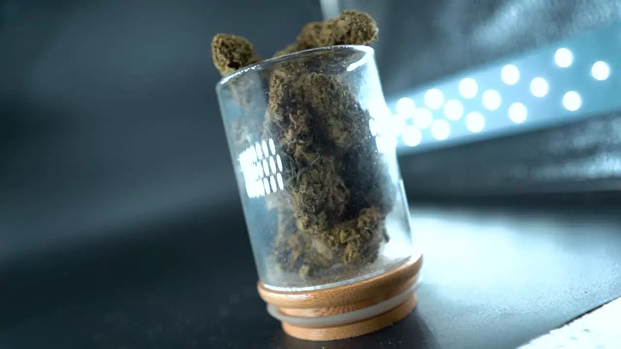 A close up detailed rotating crane shot of a cannabis plant marijuana flower in a shiny glass hybrid strains Indica and sativa 120 fps slow motion Full HD cinematic studio lighting