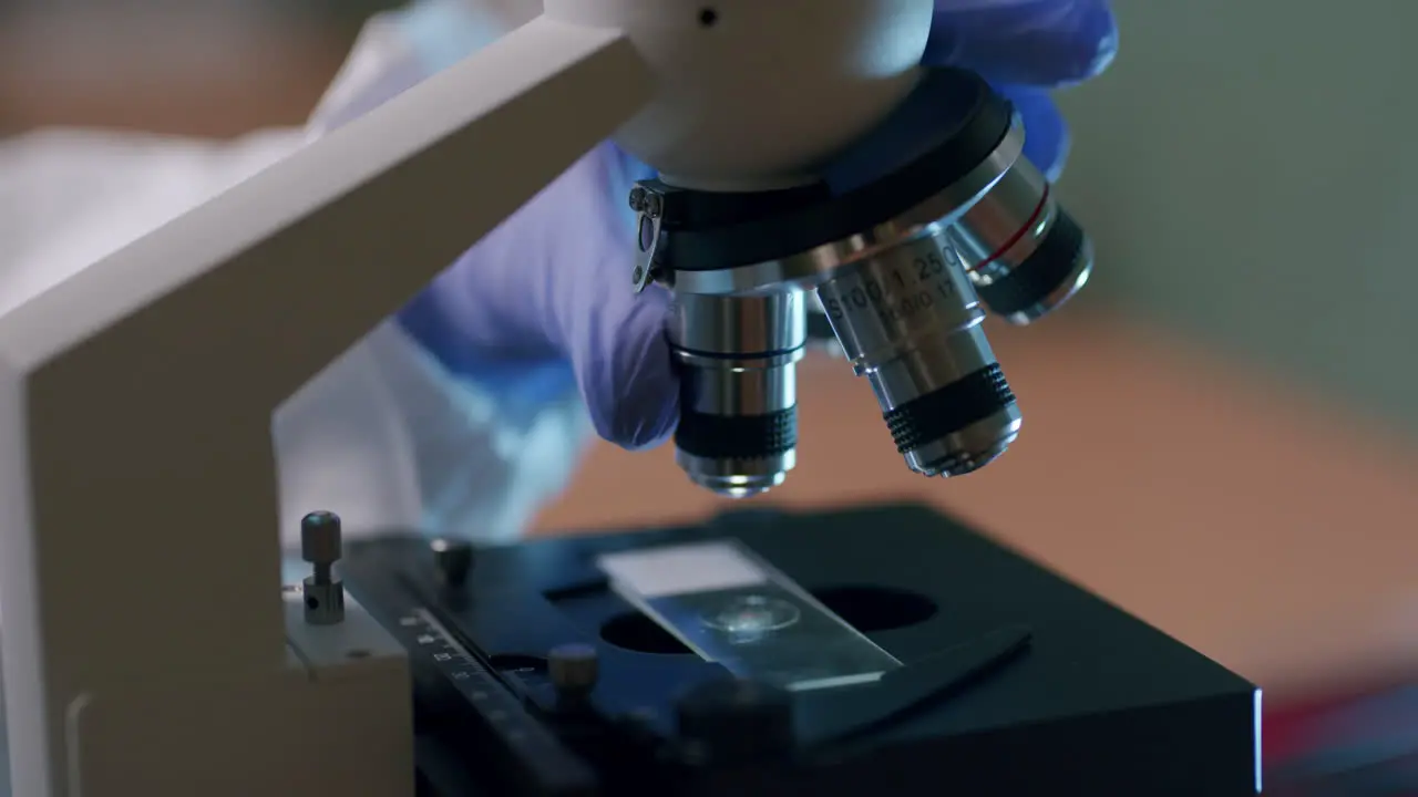 A young life scientist changes the lenses of the professional microscope in the laboratory—a close-up shot of the microscope lens turret