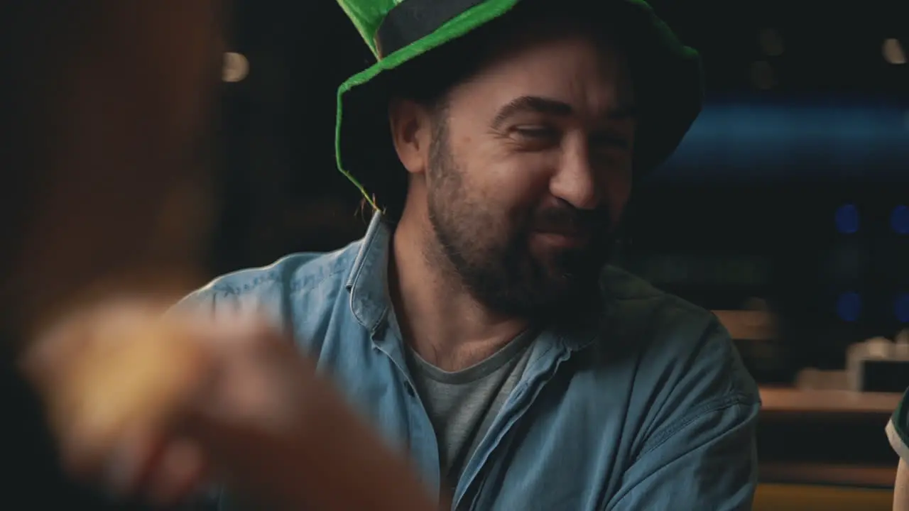 Portrait Of Happy Man In Irish Hat Drinking A Beer Mug And Talking With Friends In A Pub