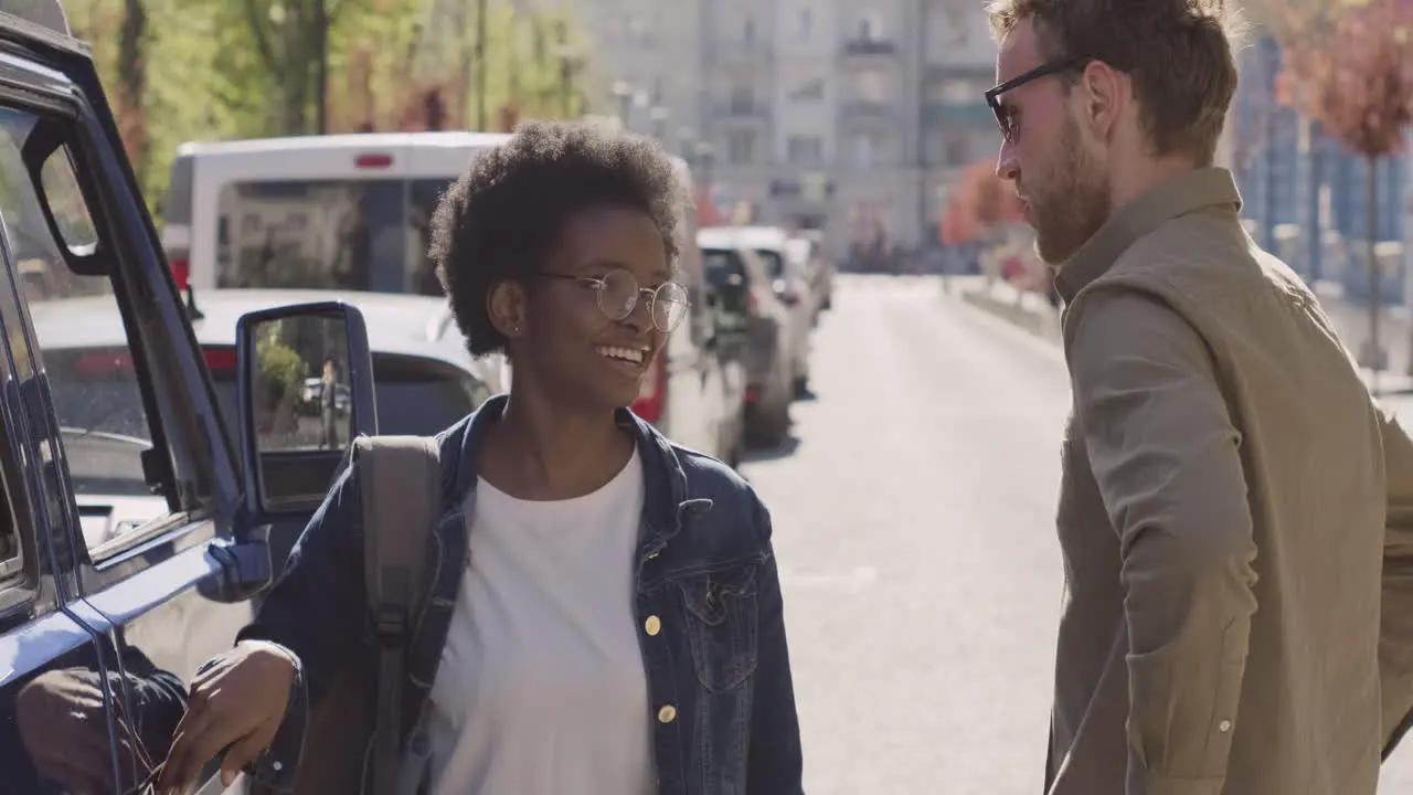 An Young Woman And A Young Man Have A Conversation Next To A Van Before A Road Trip