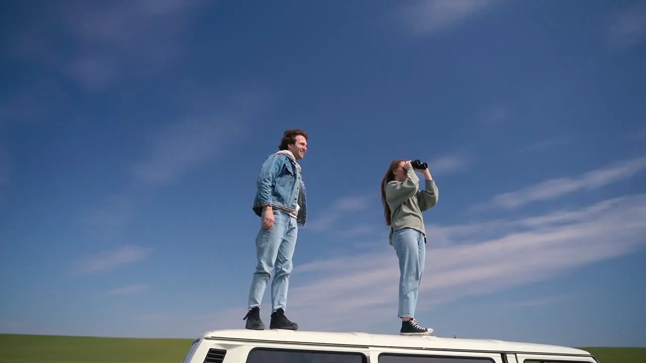 A Young Boy And Young Girl Look Around With A Pair Of Binoculars On The Roof Of A Caravan