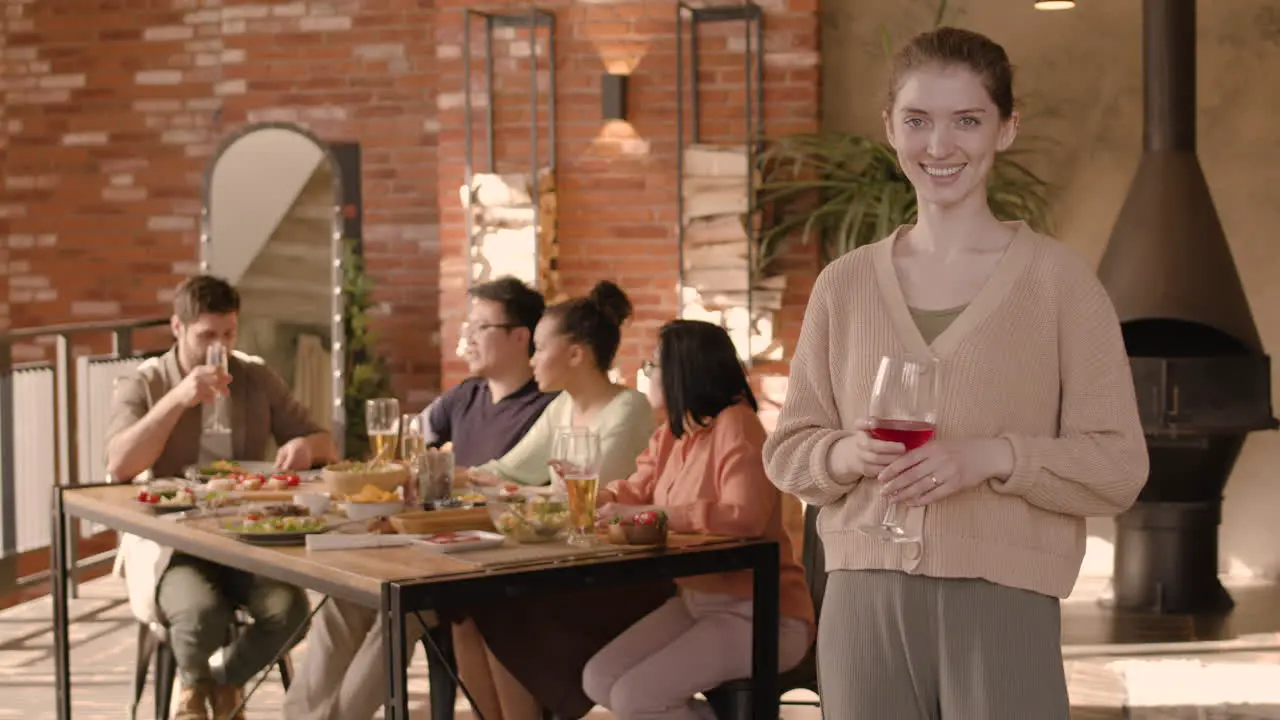 A Red Head Young Woman Checking Her Glass Of Wine At A Dinner Party