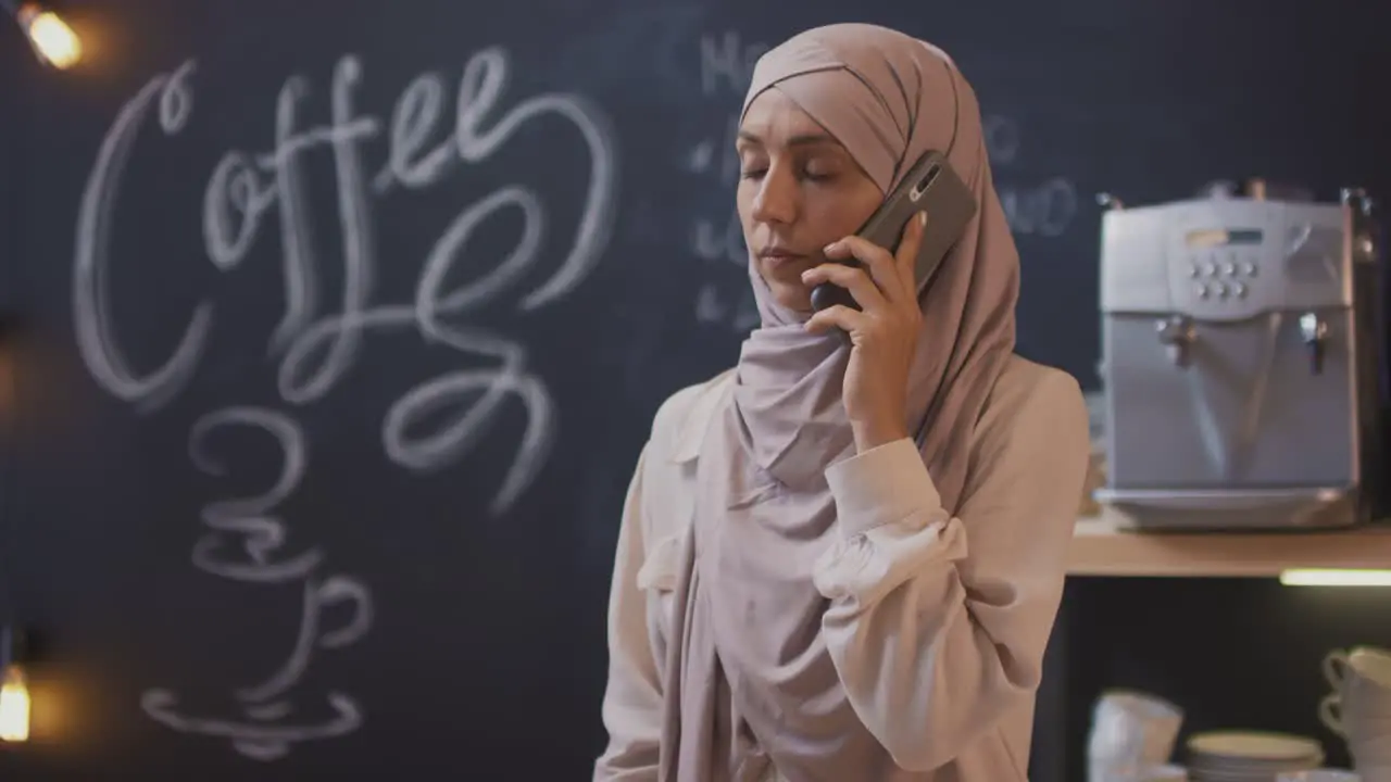 Muslim Woman Talking On The Phone In A Coffee Shop