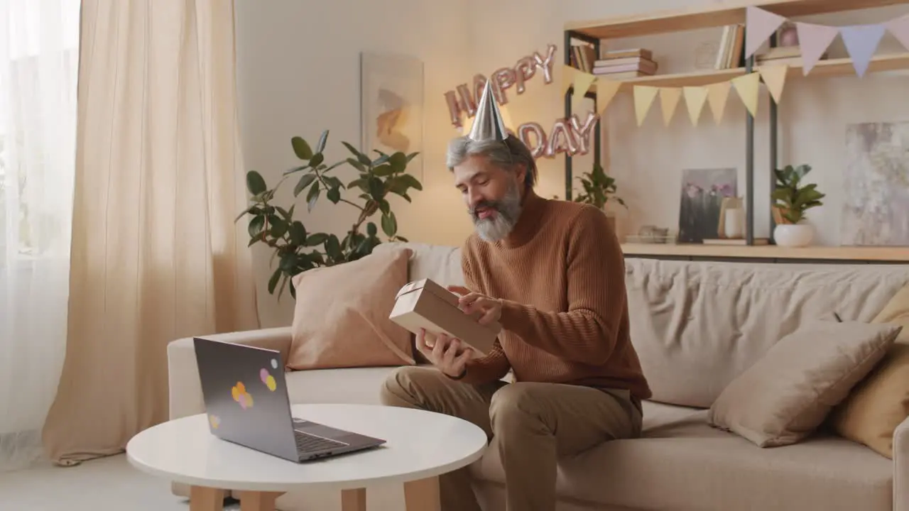 Man Celebrating Birthday Online Wearing Birthday Hats And Opening A Gift