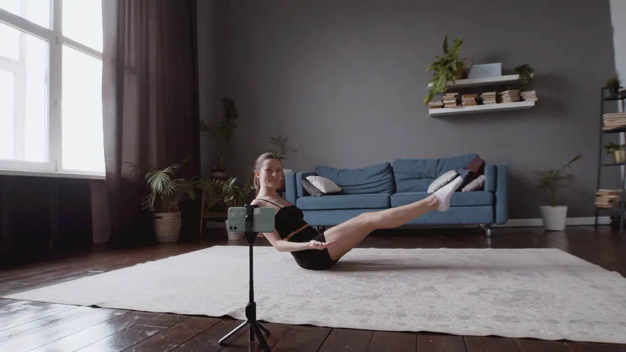 Wide Shot Of An Athletic Female Vlogger Giving An Online Fitness Class In Front Of Her Smartphone Camera