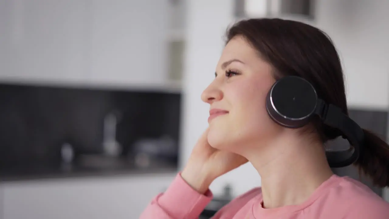 Portrait Of Smiling Woman Dancing At Kitchen In Headphones