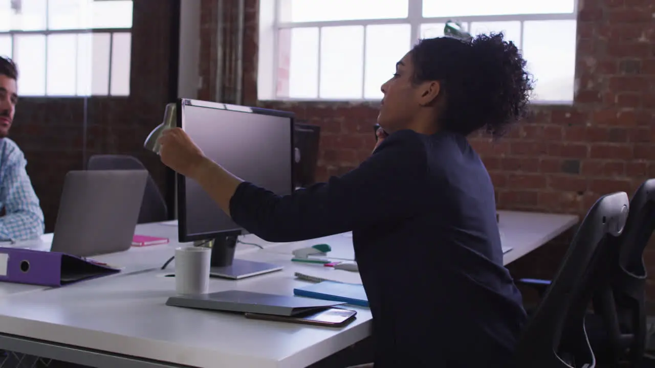 Diverse work colleagues exchanging documents sitting in office in front of computer