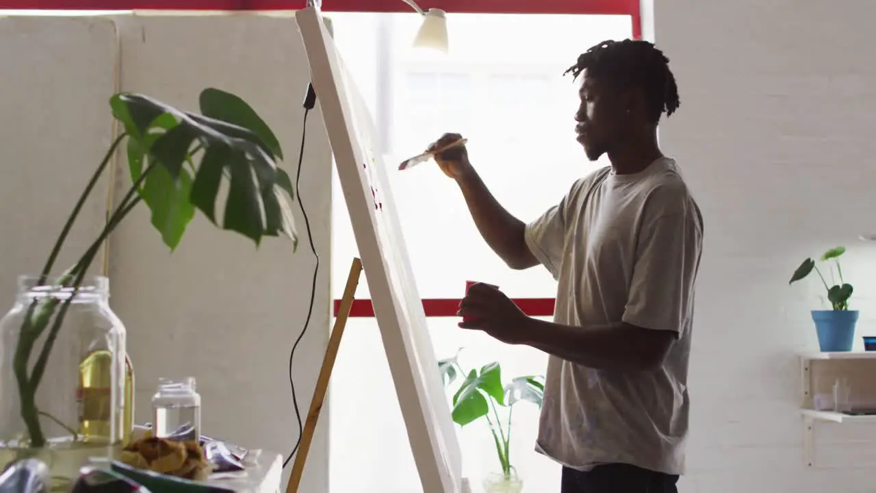 Side view of african american male artist painting on canvas at art studio