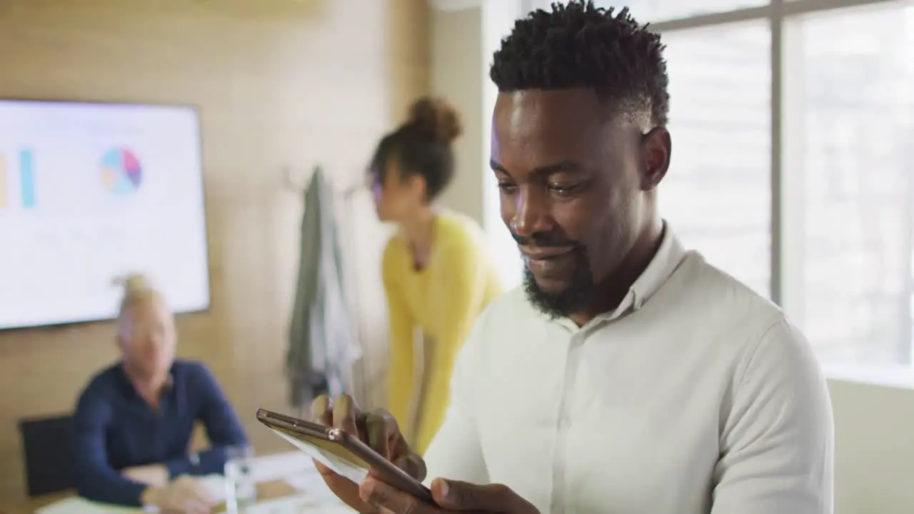 Portrait of happy african american businessman with tablet in creative office