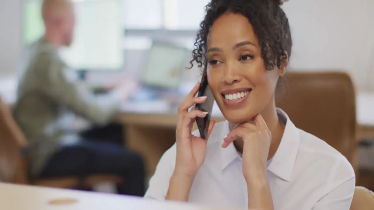 Happy african american businesswoman talking on smartphone in creative office