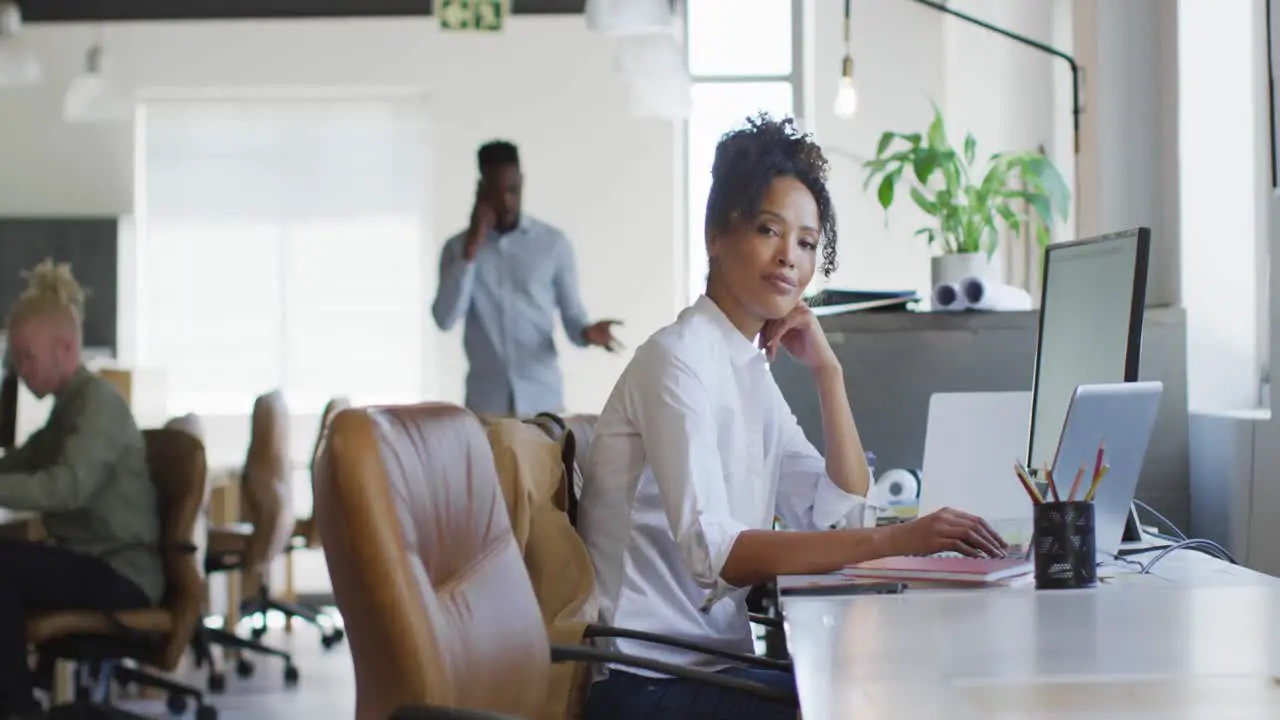 Portrait of happy african american businesswoman with laptop in creative office