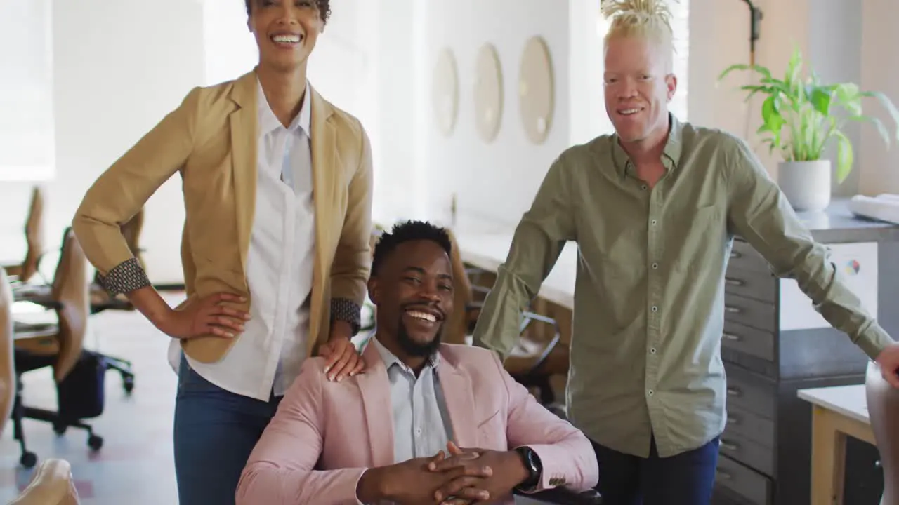 Portrait of happy diverse business people with disabled colleague in creative office