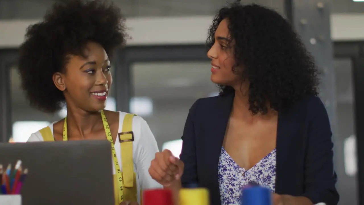 Mixed race colleagues sitting in office and discussing work over laptop