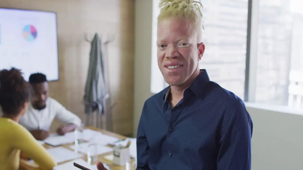 Portrait of happy albino african american businessman with tablet in creative office