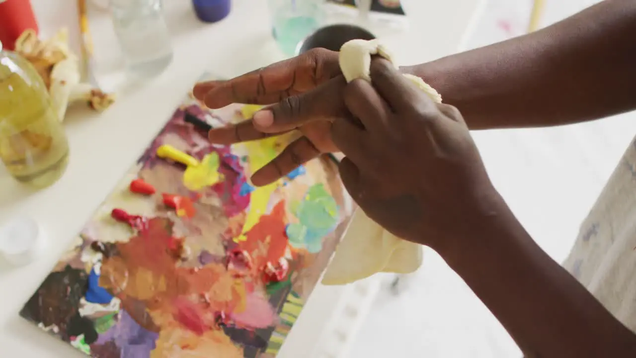 Mid section of african american male artist cleaning his hands at art studio