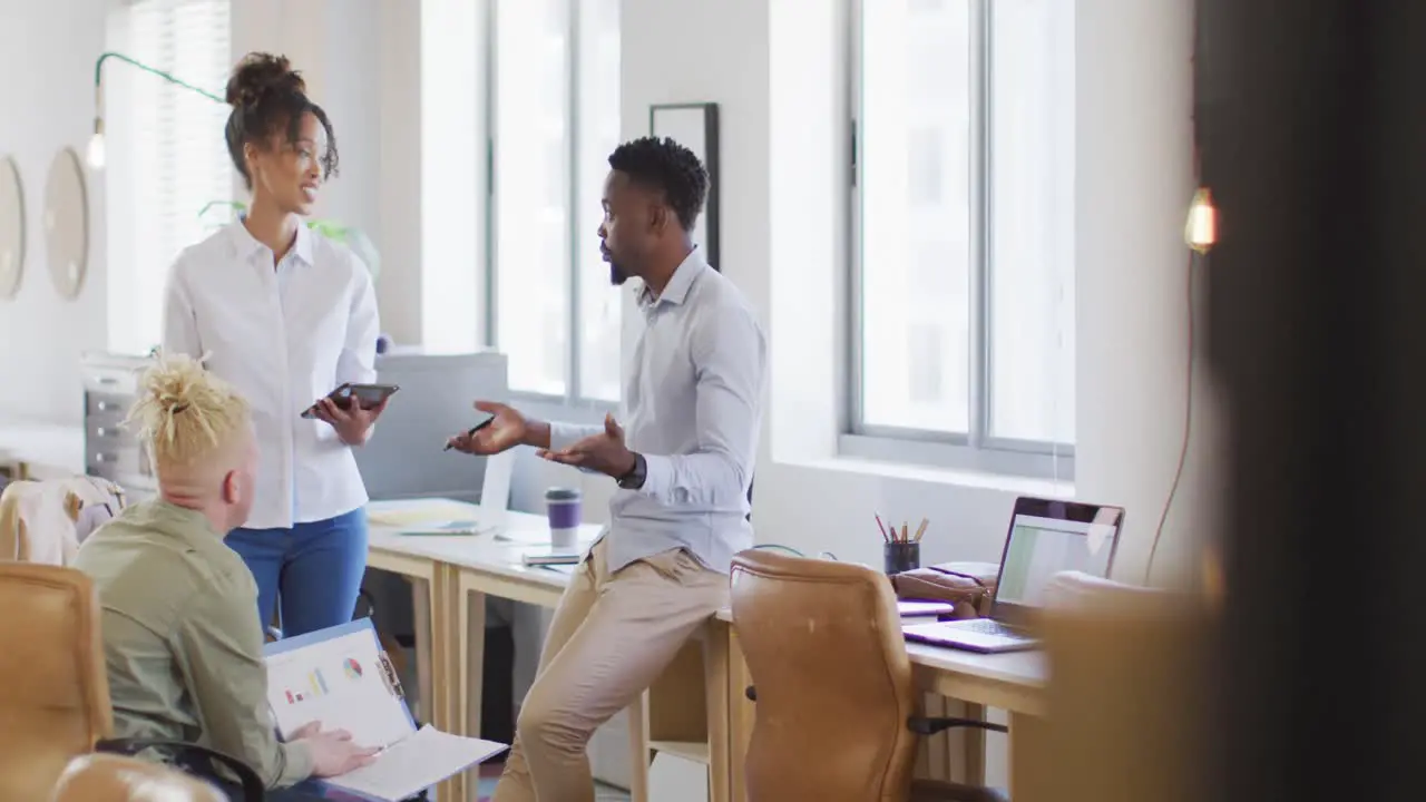 Happy diverse business people discussing with tablet in creative office