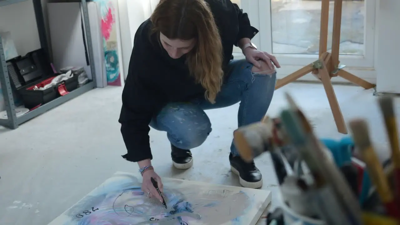 Female artist drawing on a canvas on the floor of a home studio