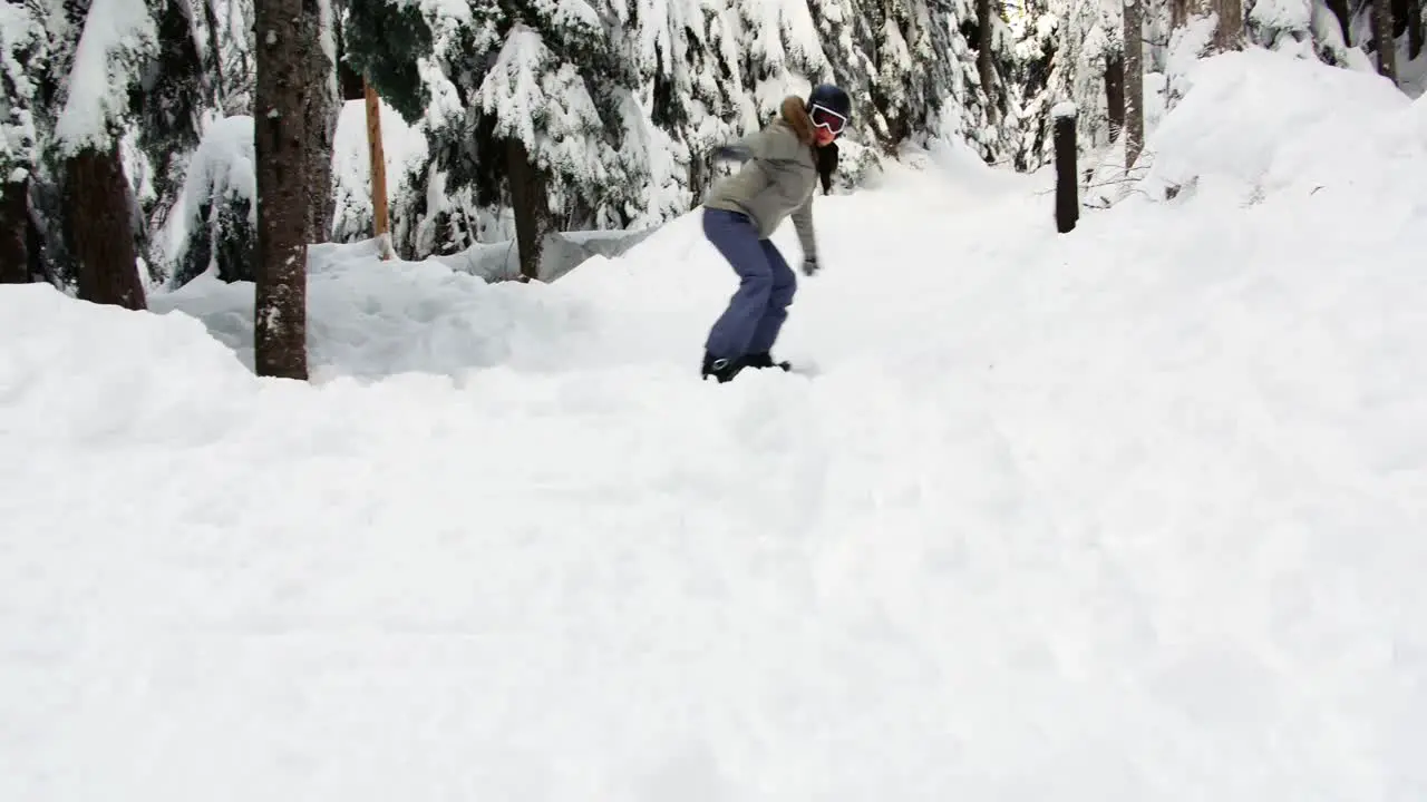 Woman snowboarding through forest 4k