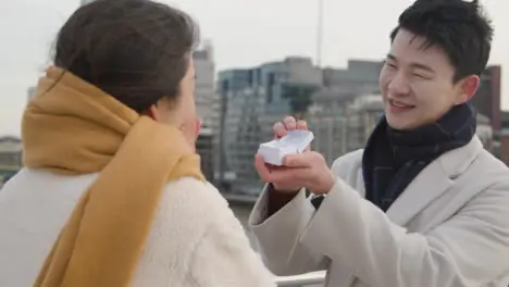 Young Asian Couple With Romantic Man Proposing To Woman Against City Skyline 2