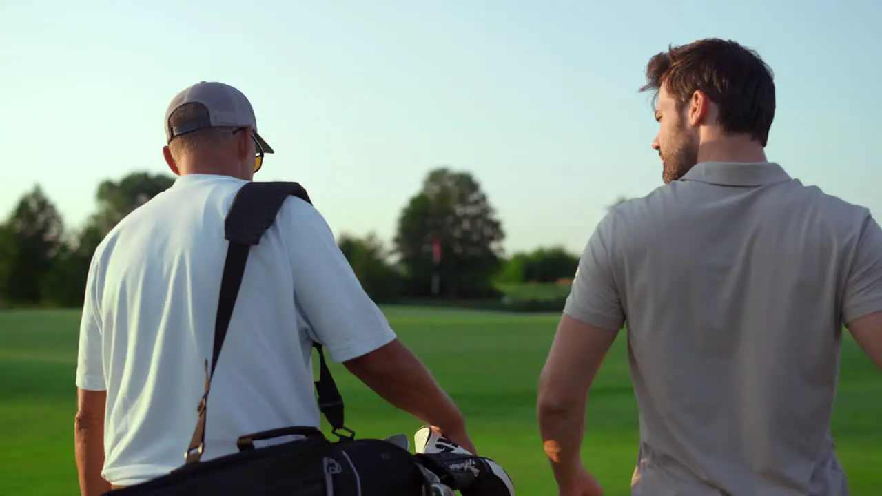 Dad son going fairway course Two golfers take sport equipment clubs outdoors