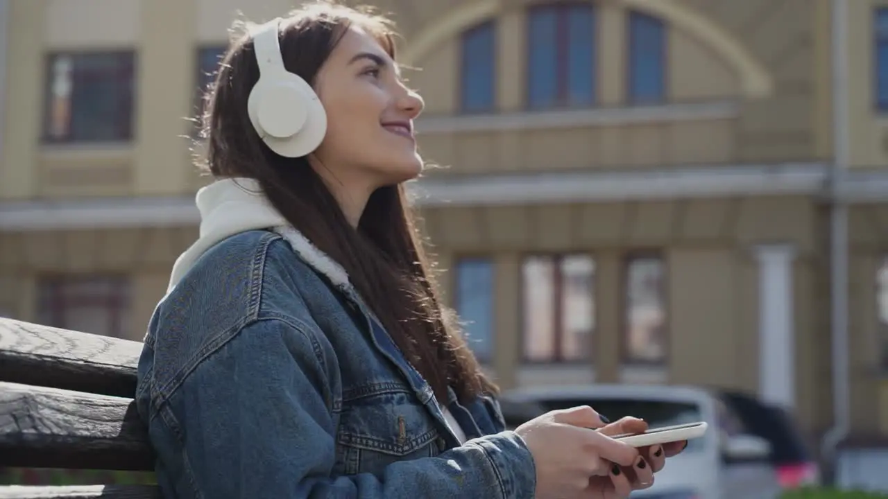 Young Woman Listening To Music Sitting In A Park In The City