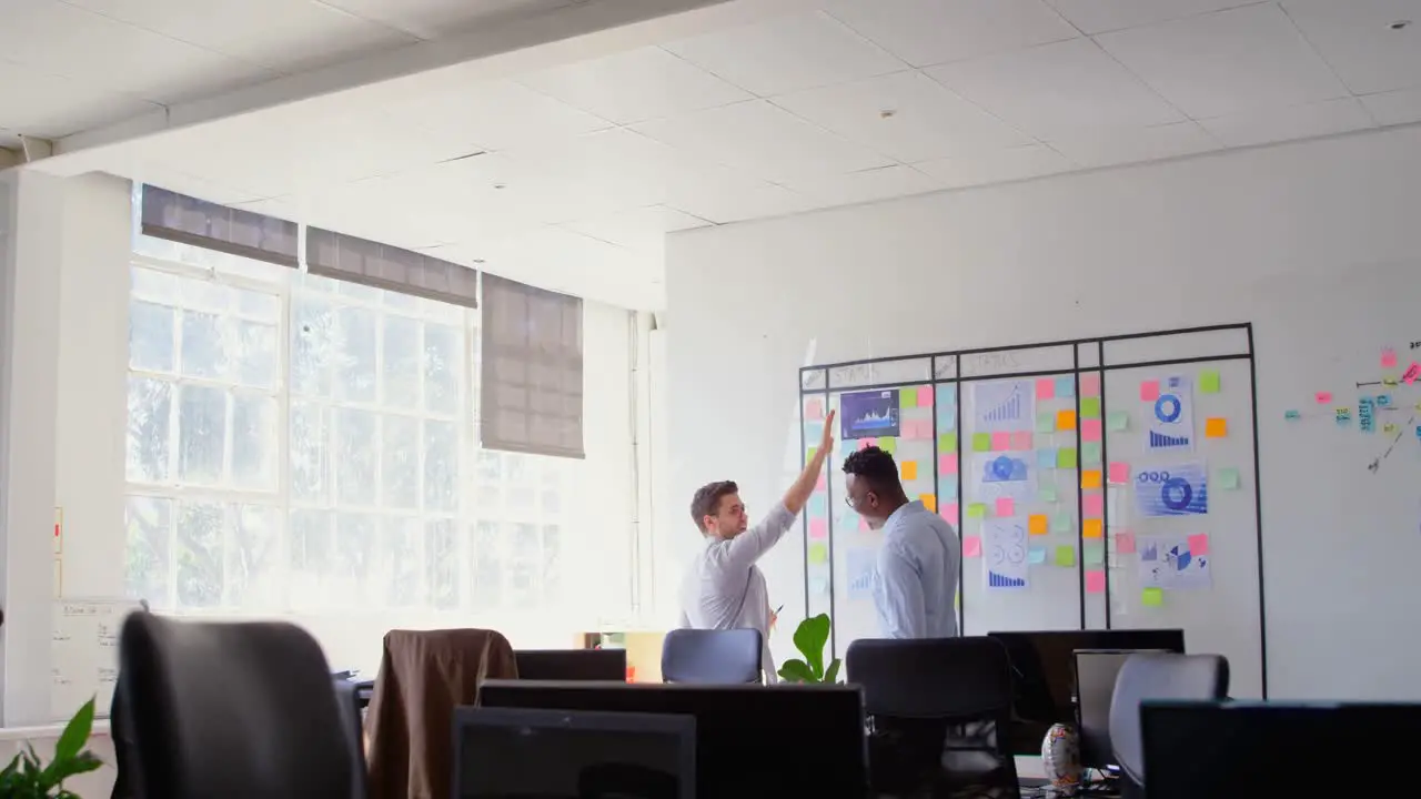 Side view of young cool mixed-race business team working and giving high-five in a modern office 4k