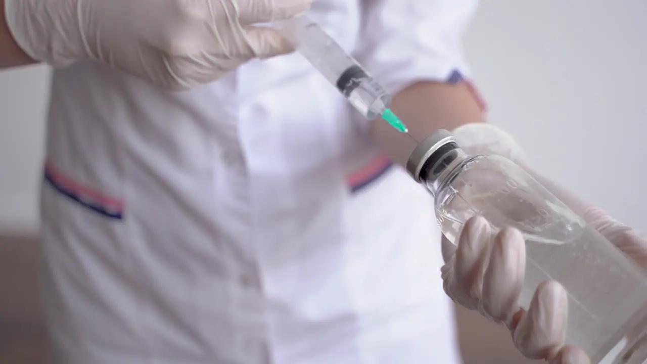 Close Up Of Hands Of A Doctor Filling A Vial With A Syringe