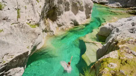 Carefree young woman jumping from a cliff to swim