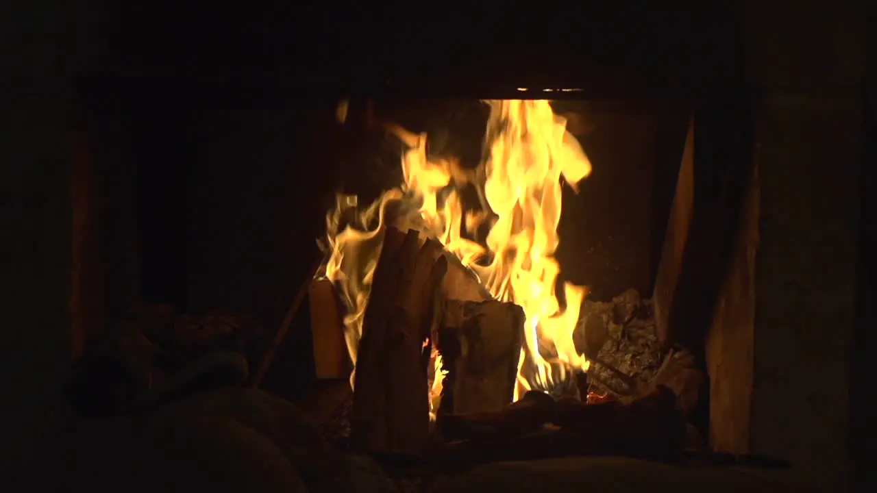 Orange flames burning brightly in cozy looking fireplace filmed as medium close up in slow motion