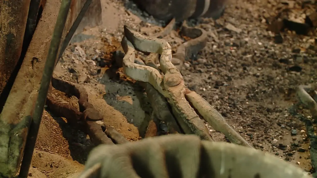 blacksmith tongs lying on ashes in front of ancient traditional oven focus shift