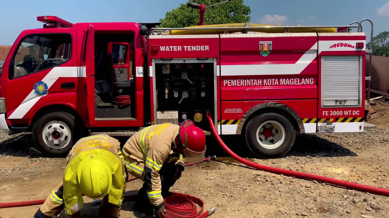 Firefighters roll up the water tubes after a fire was extinguished