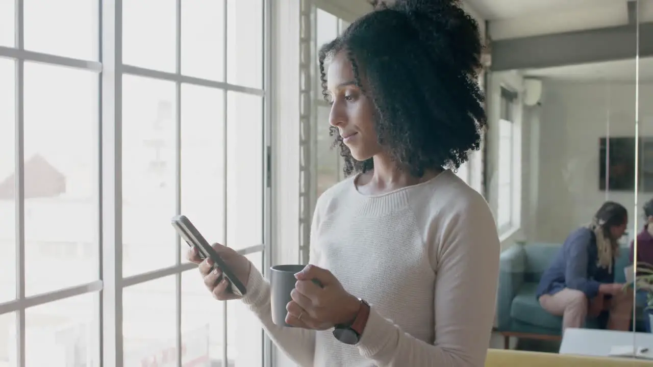 Busy biracial casual businesswoman using smartphone in creative office slow motion