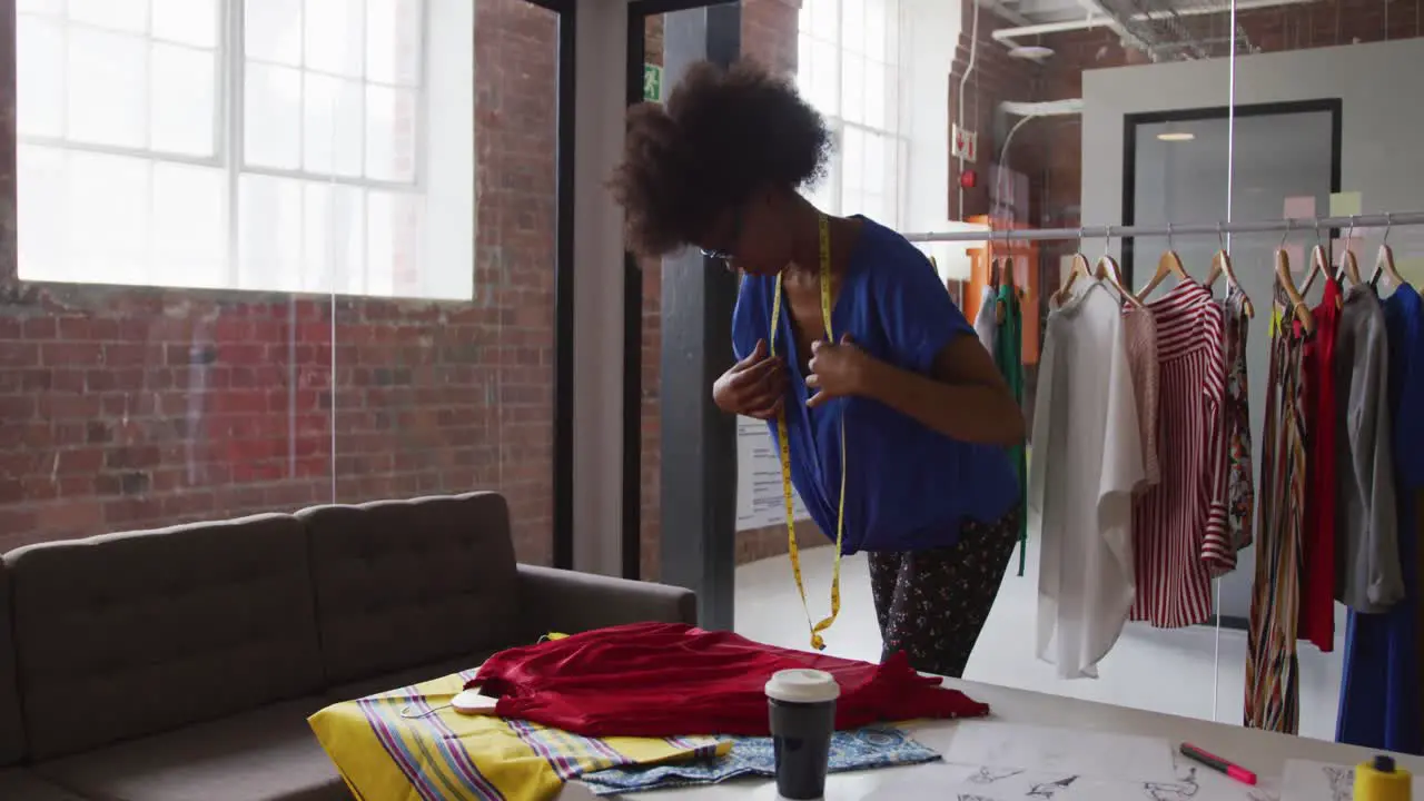 African american female fashion designer taking measurements of clothing with a tape measure