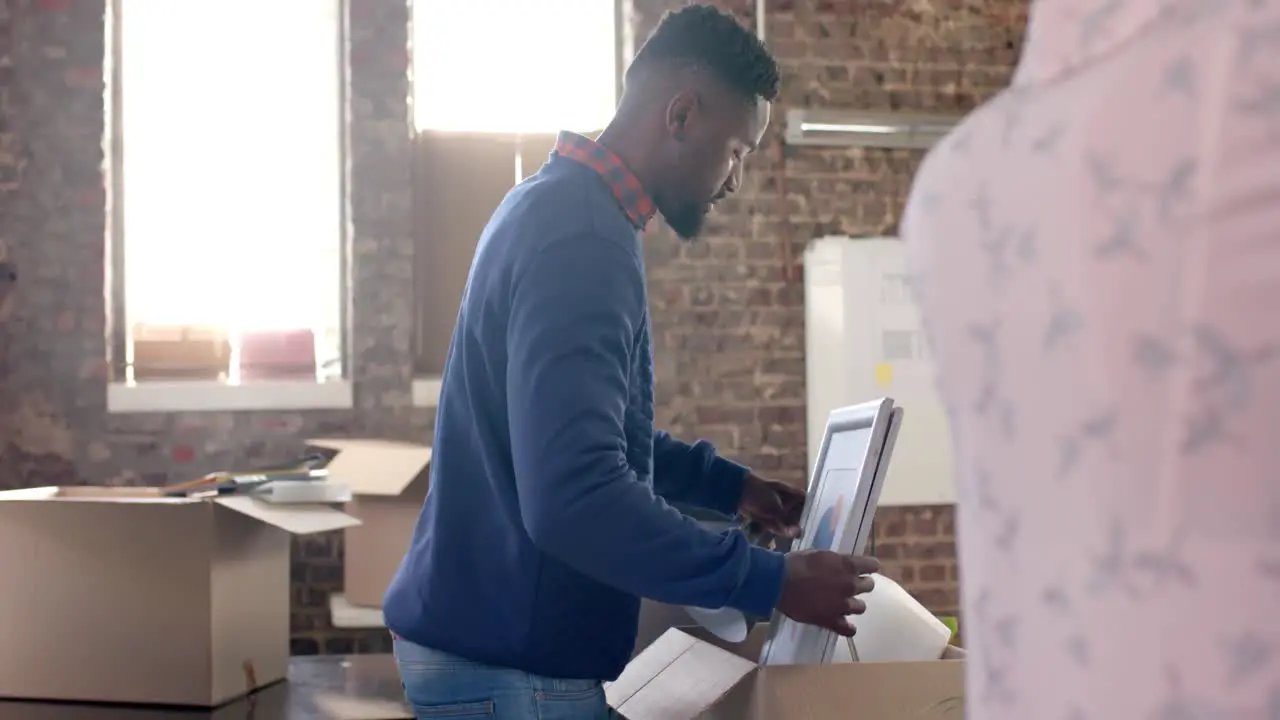 Diverse colleagues packing boxes with documents and office items in creative office in slow motion