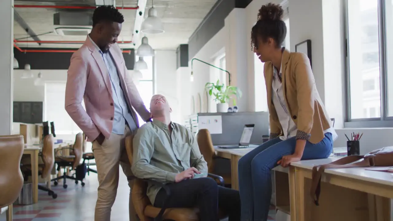 Portrait of happy diverse business people discussing at table in creative office