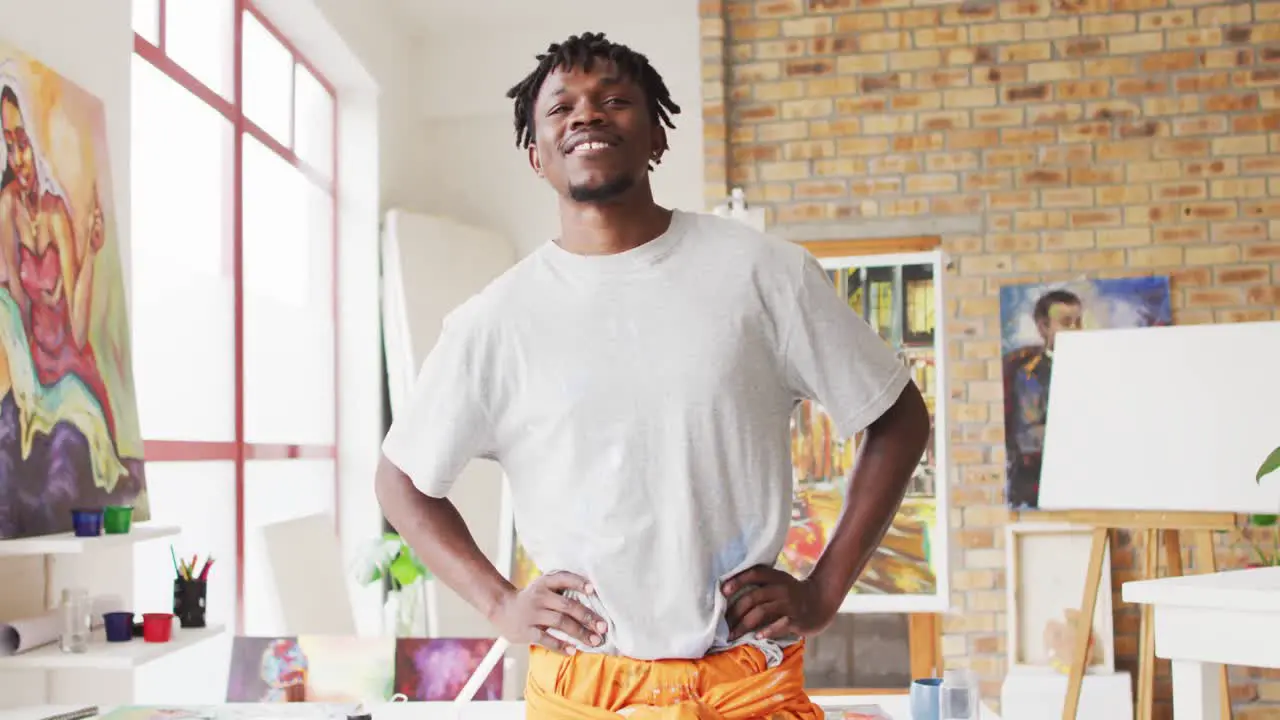 Portrait of african american male artist with hands on hips smiling at art studio