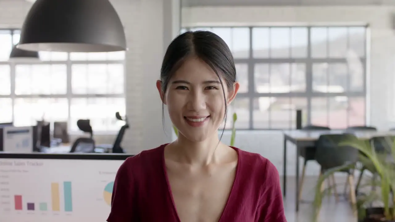 Portrait of happy asian casual businesswoman in creative office in slow motion