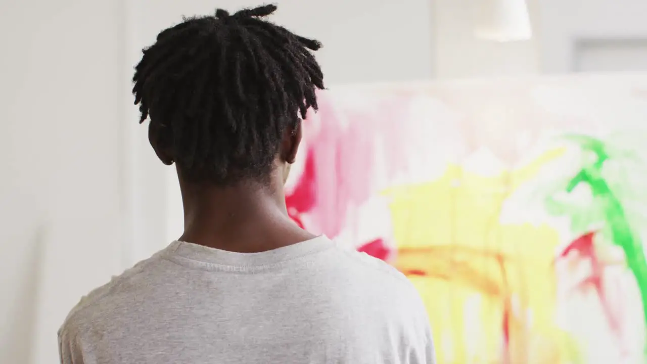 Rear view of african american male artist painting on canvas at art studio