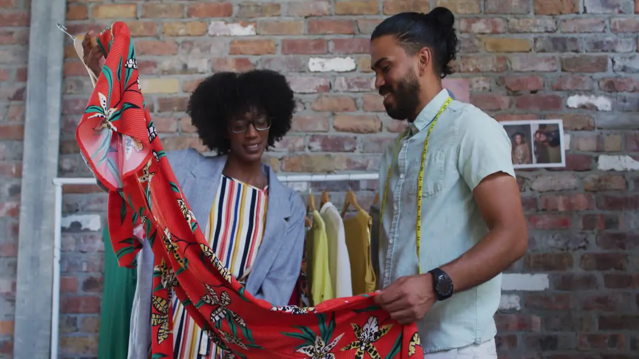 Diverse male and female fashion designers in discussion at work looking at dress