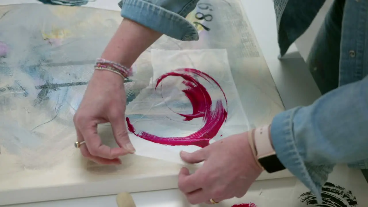 Female artist brushing arranging paper asset on canvas in a home studio