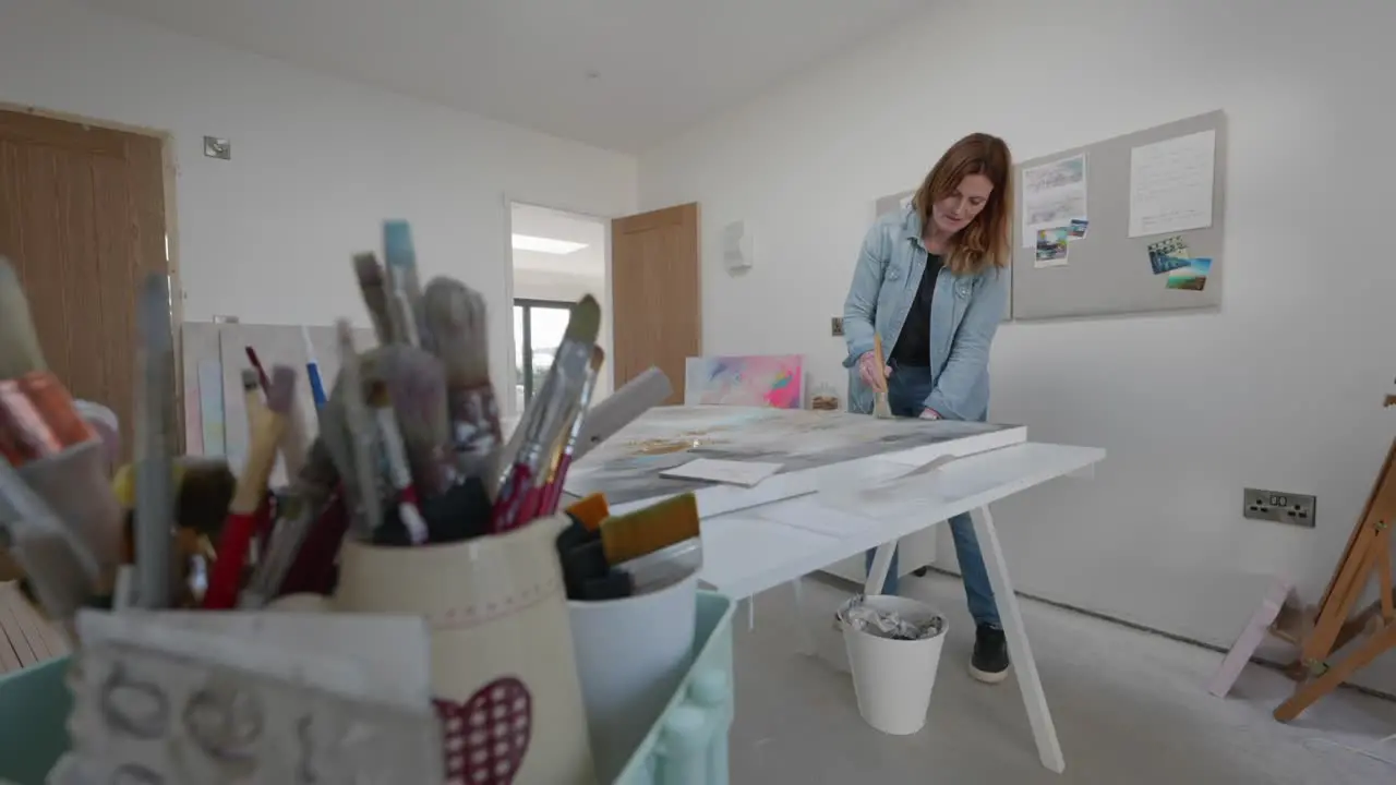 Female artist brushes large canvas in home studio