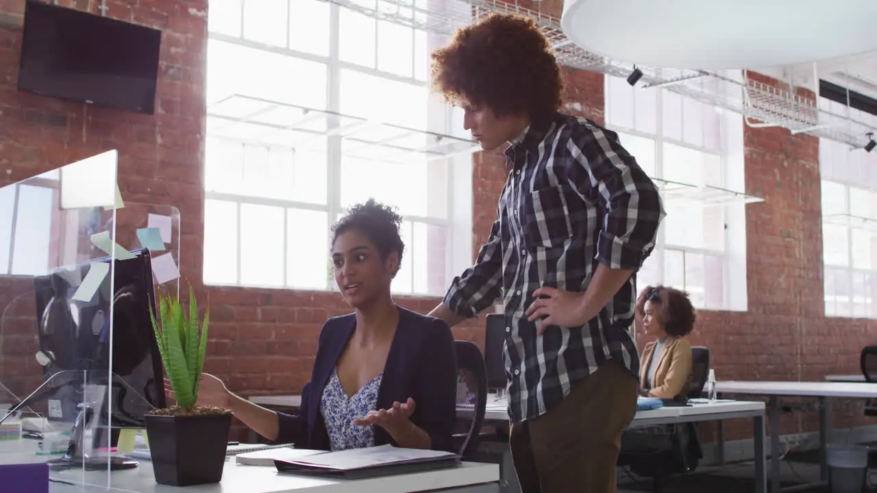 Diverse male and female colleagues discussing over computer screen in office