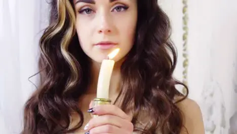 Young brunette woman snuffs off a candle