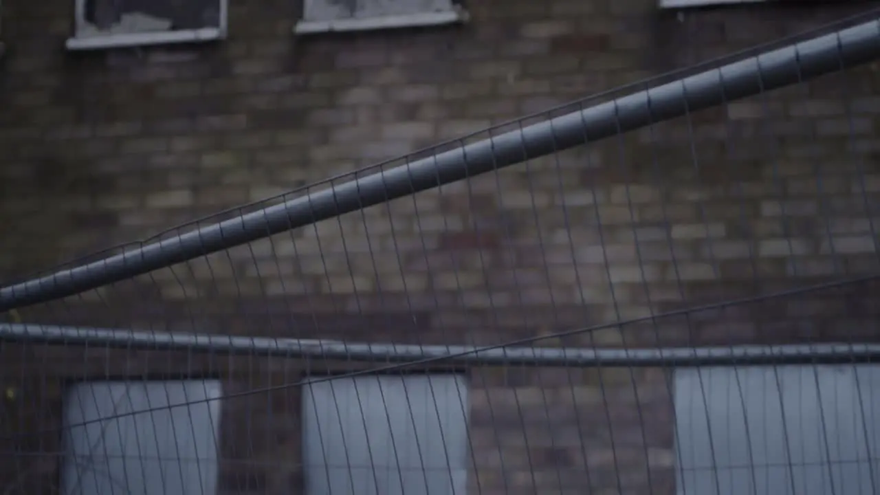 Dangerous brick building with metal shutters after fire surrounded by fencing