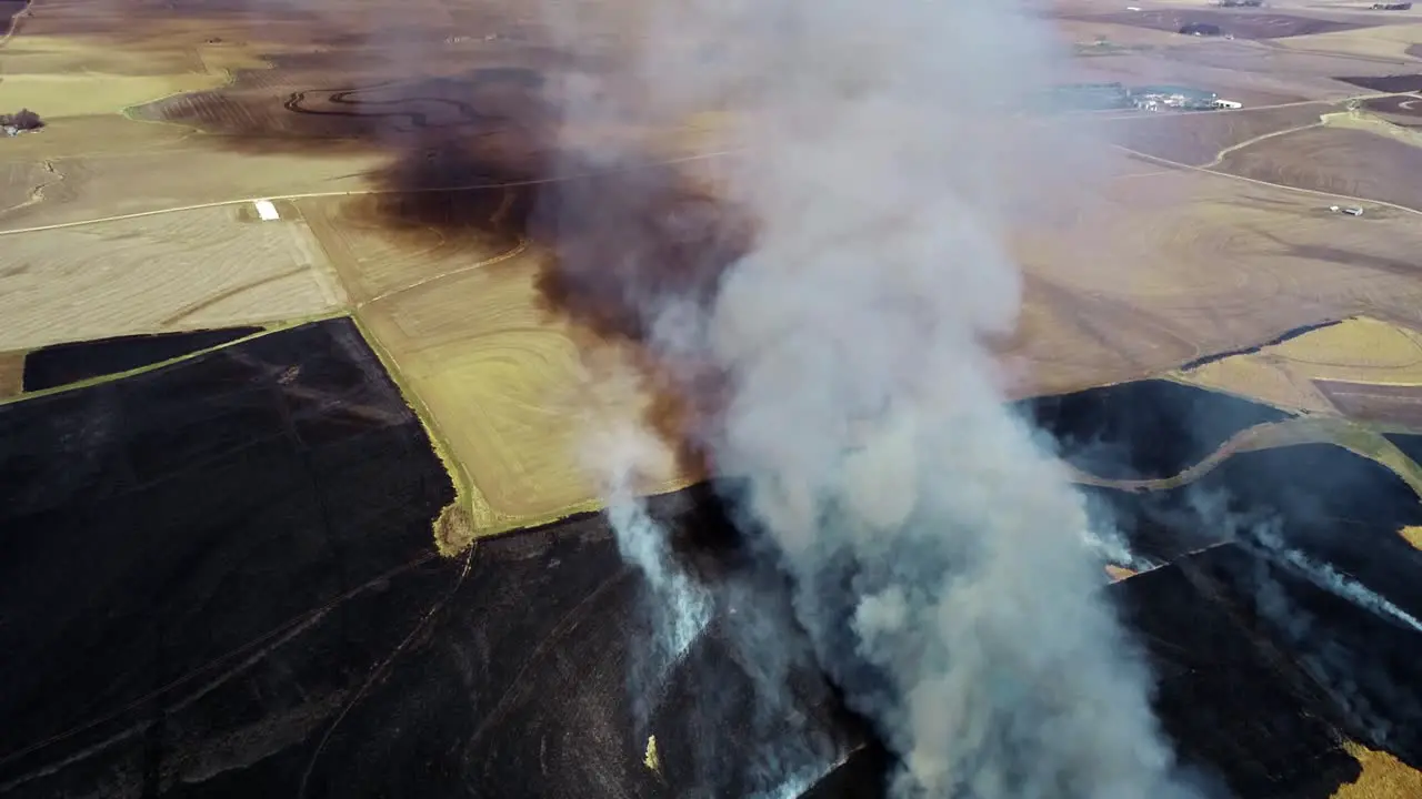 Aerial view of large smoke cloud and prairie burning surrounded by farmland