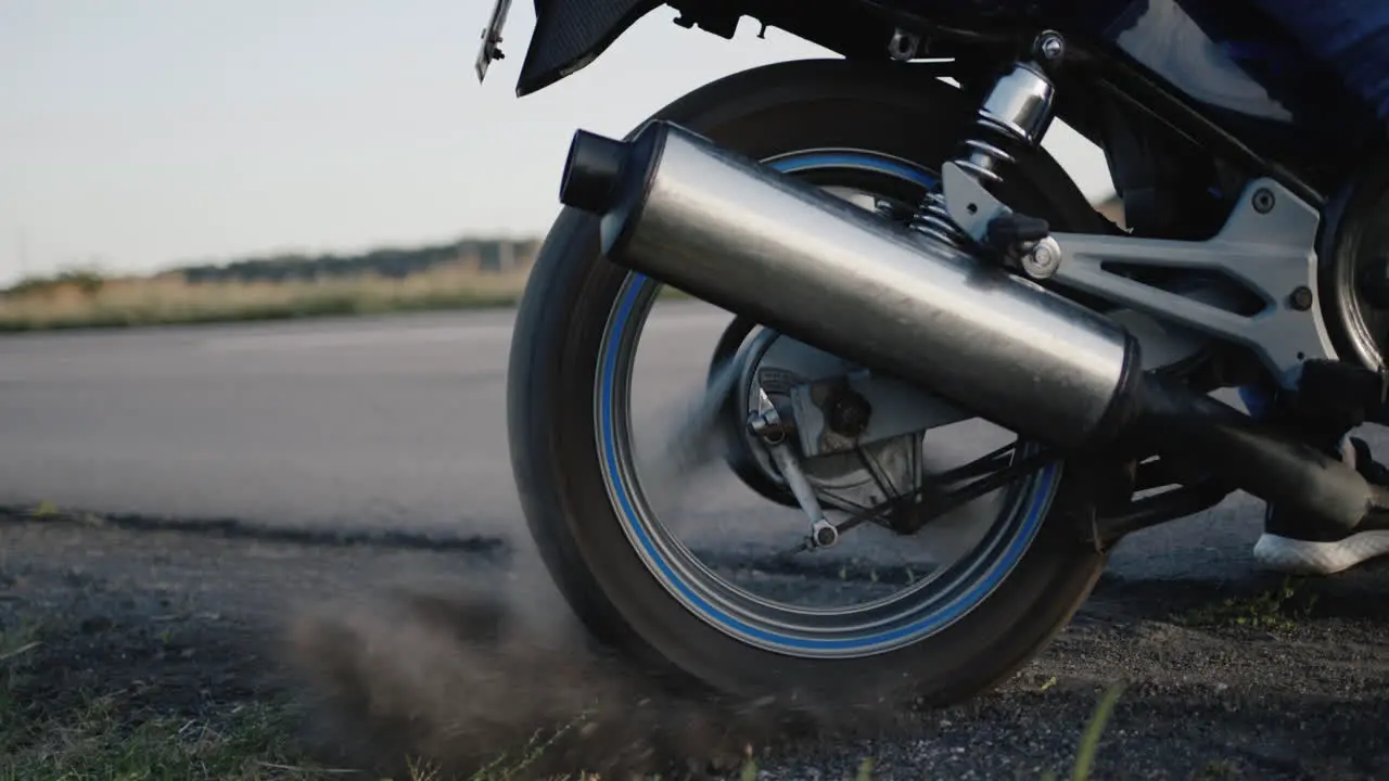 The wheel of the motorcycle skids through gravel