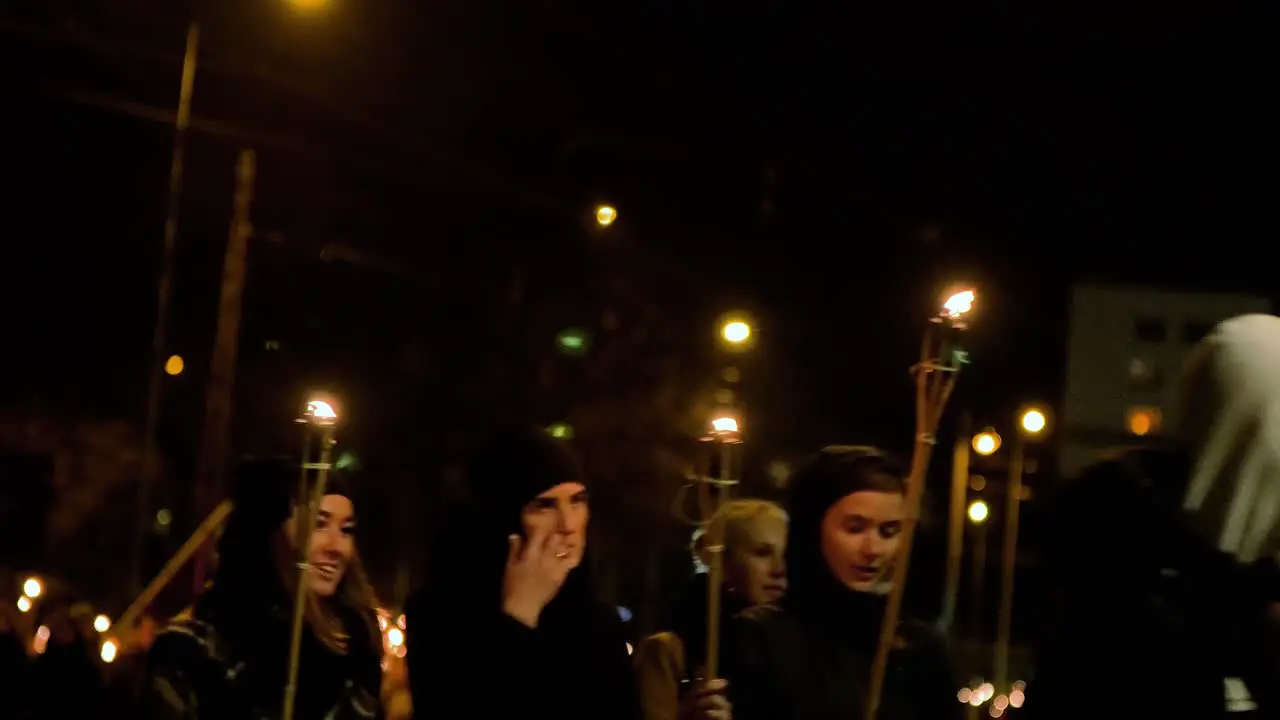 People going in a patriotic torchlight procession in Liepaja city on Lacplesa day  autumn evening city landscape traffic lights medium shot