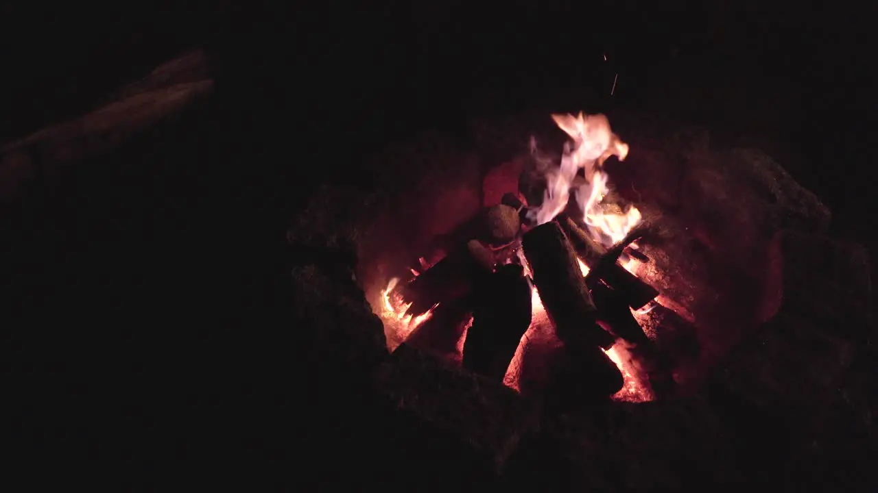 Campfire burning at night in the dark with space in the left