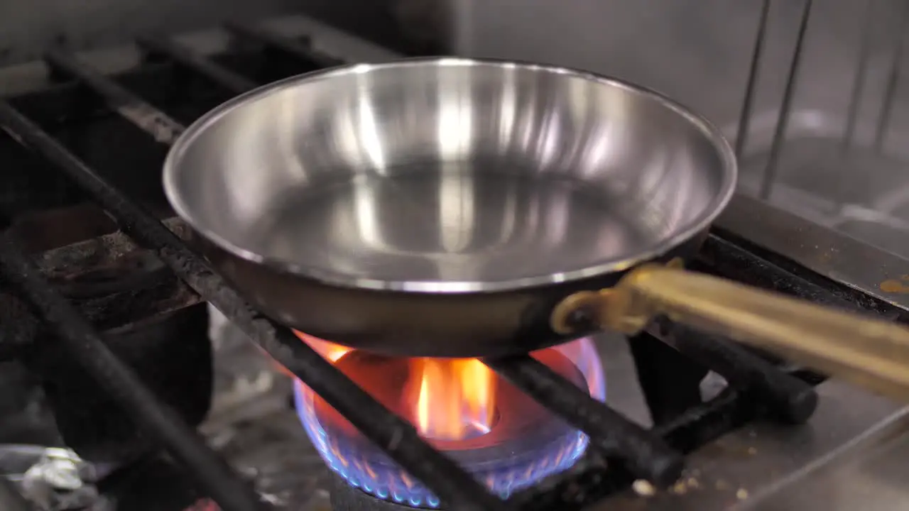 Unrecognizable chef putting frying pan on turned on gas stove close up