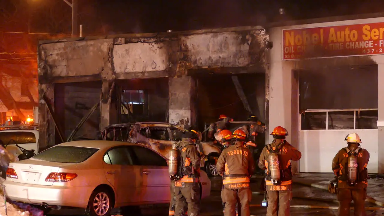 Firefighters fighting burning commercial building flames in Toronto back view